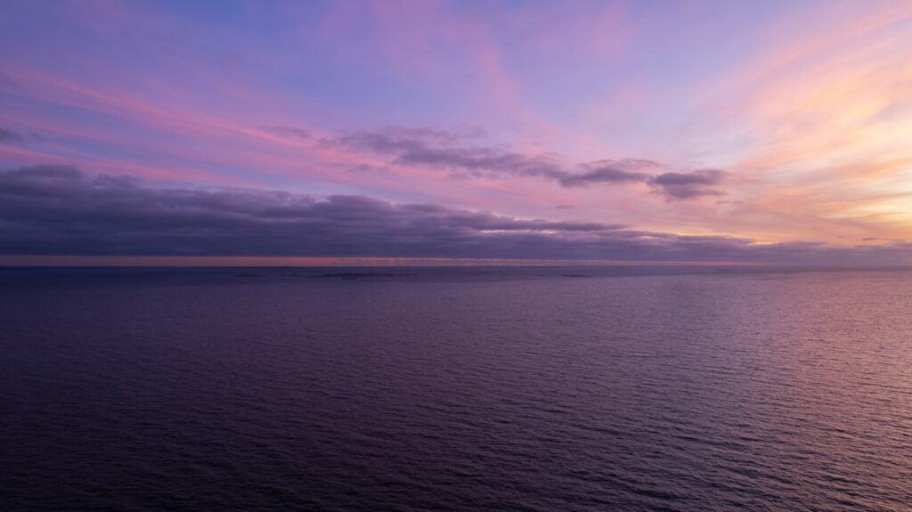 a sunset over a body of water with clouds in the sky